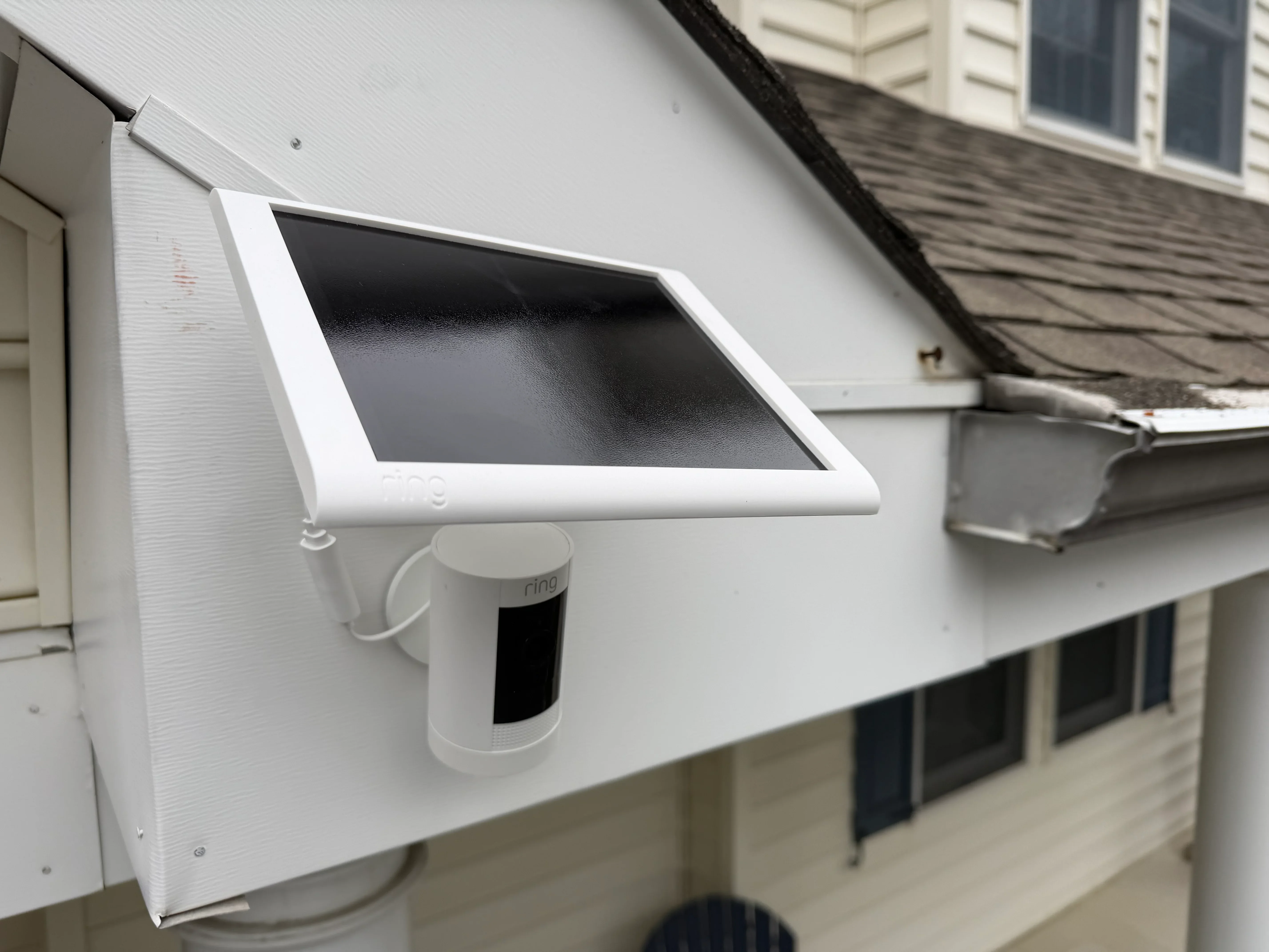 Ring doorbell and solar tablet mounted on white vinyl siding with metal gutter