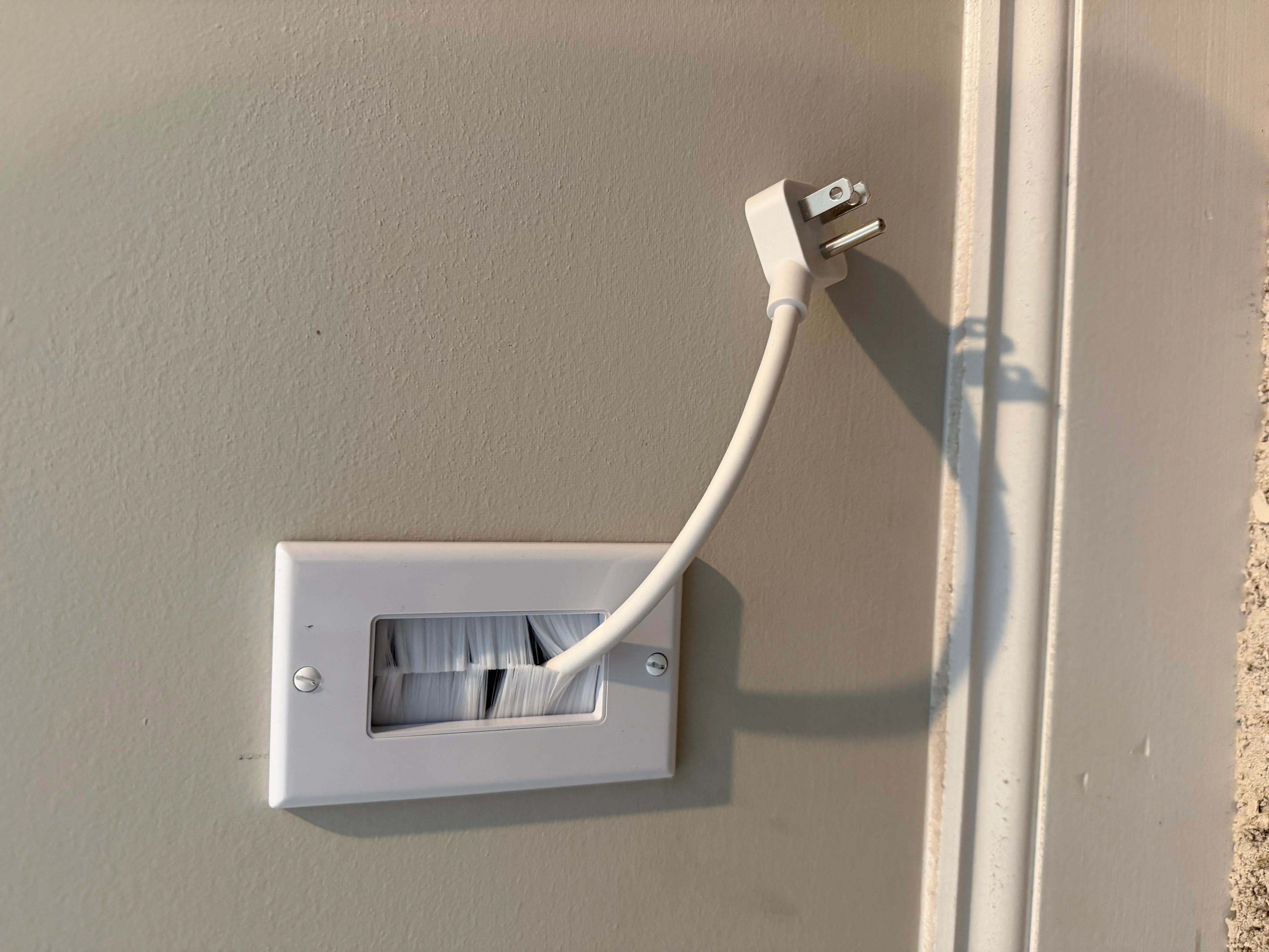 White electrical outlet box with white power cord installed in drywall