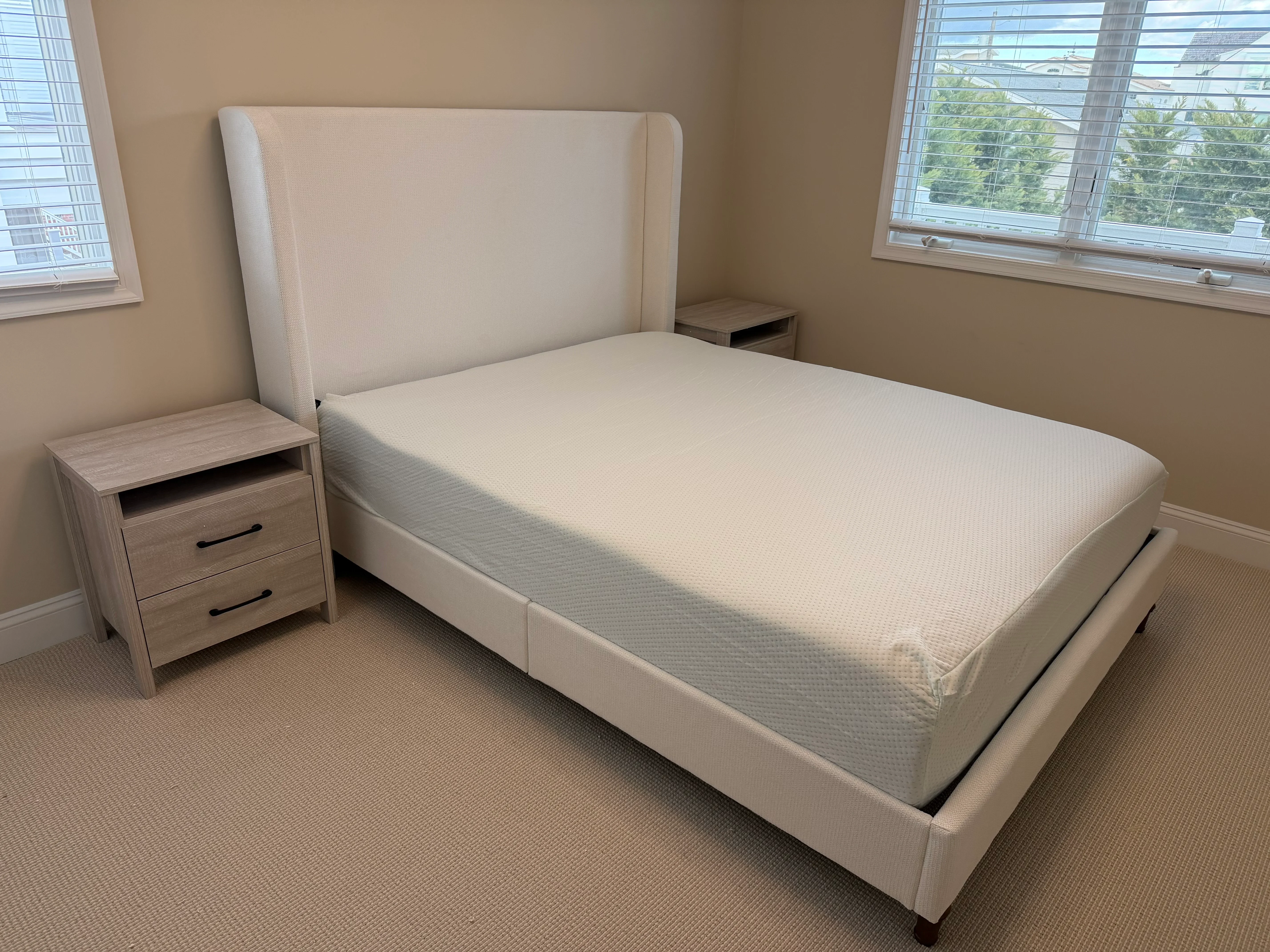 Assembled upholstered bed with headboard, light wood nightstand, and mattress in bedroom