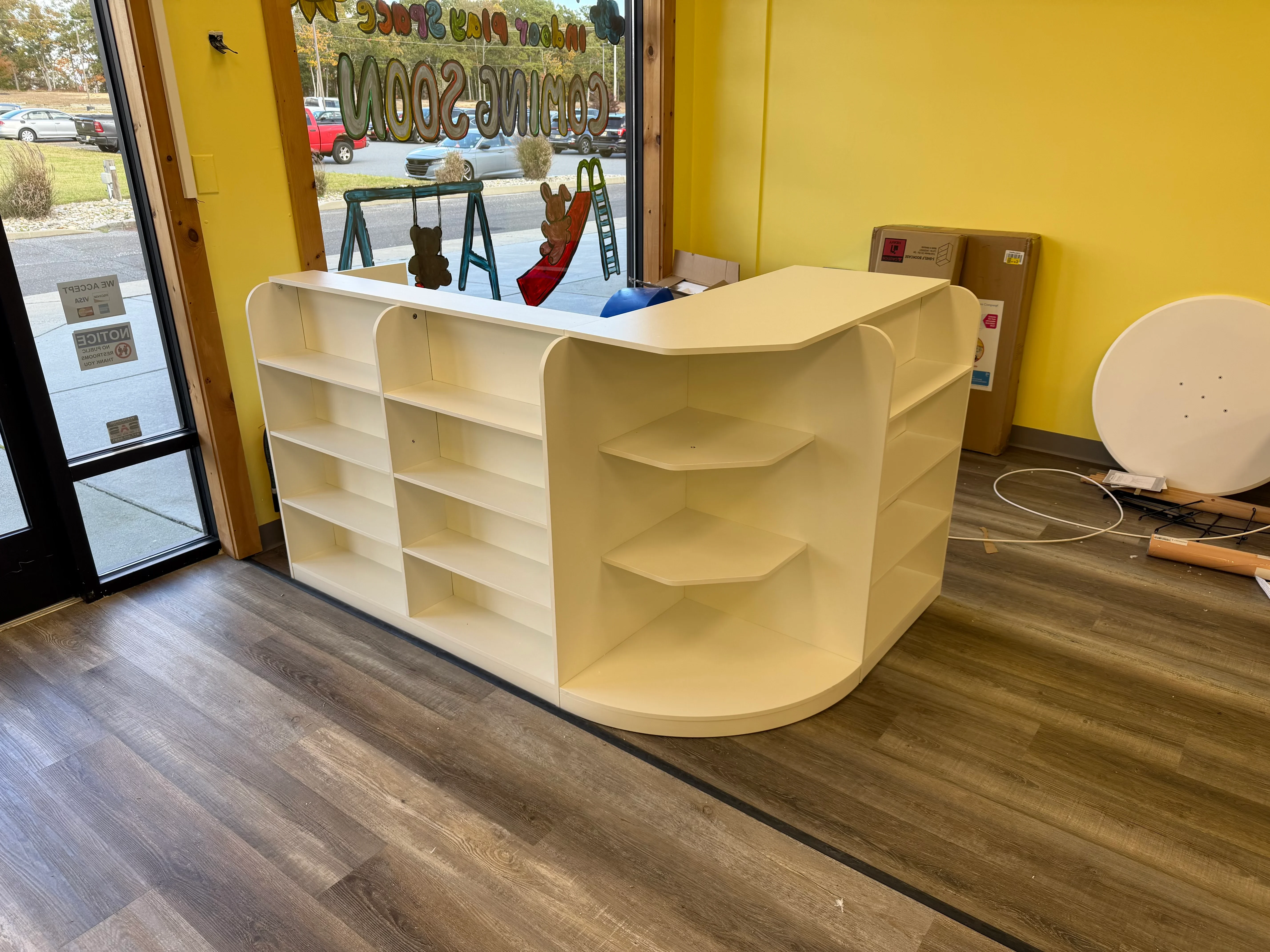 Cream-colored retail counter with curved shelving and open display compartments in commercial space