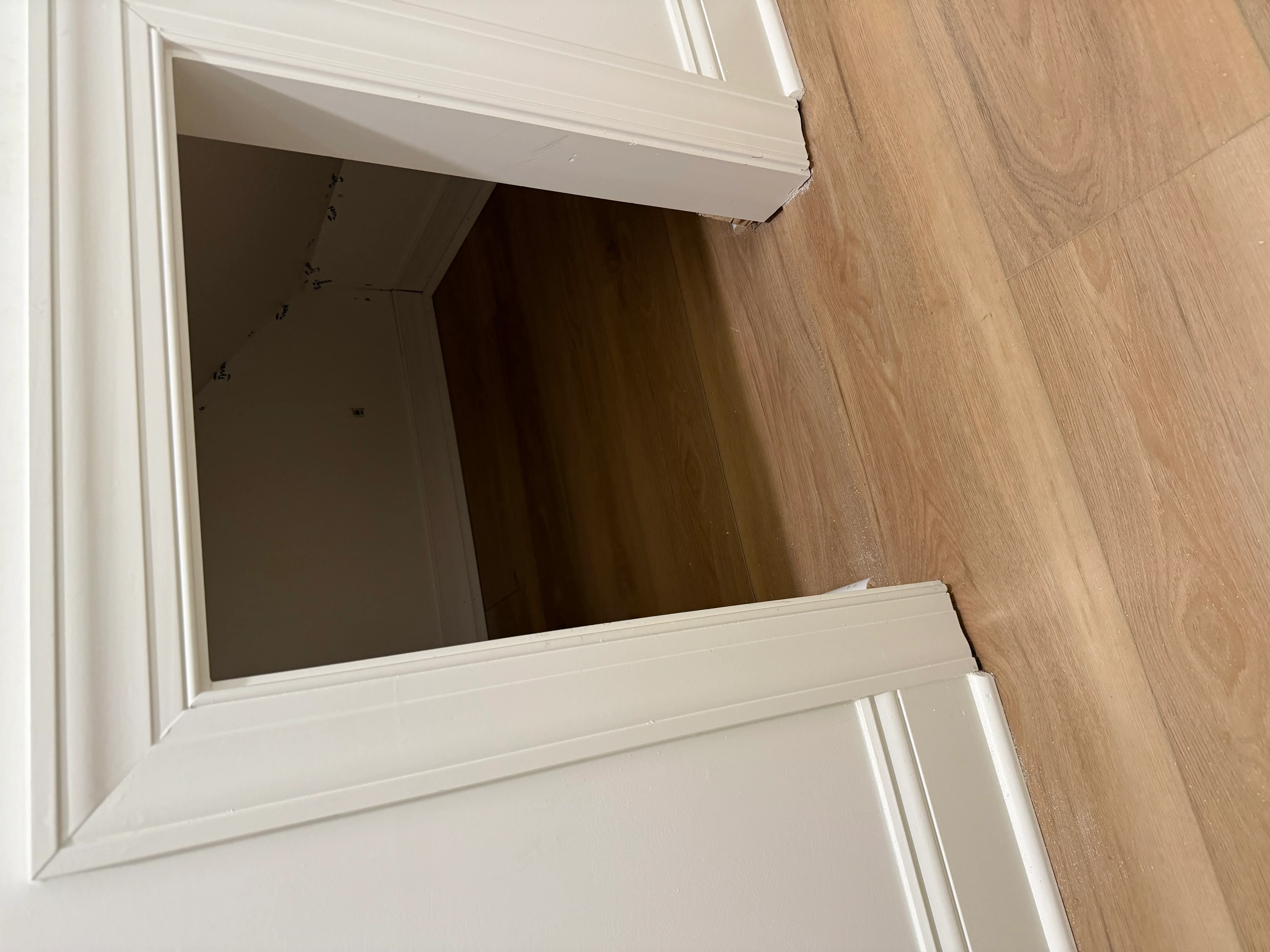 White painted interior door frame with trim installed against hardwood flooring