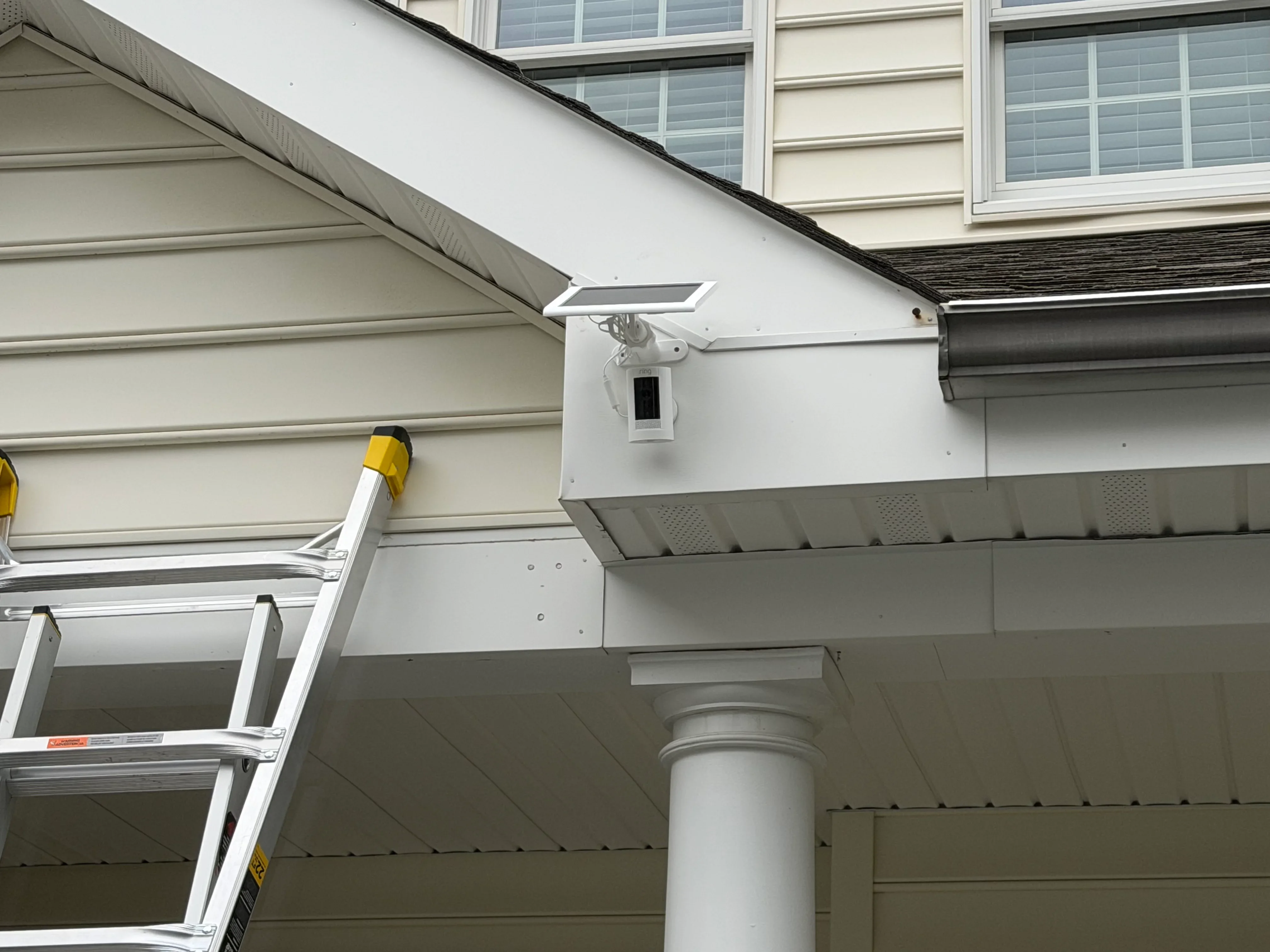 Solar security light with motion sensor mounted on white vinyl soffit and siding
